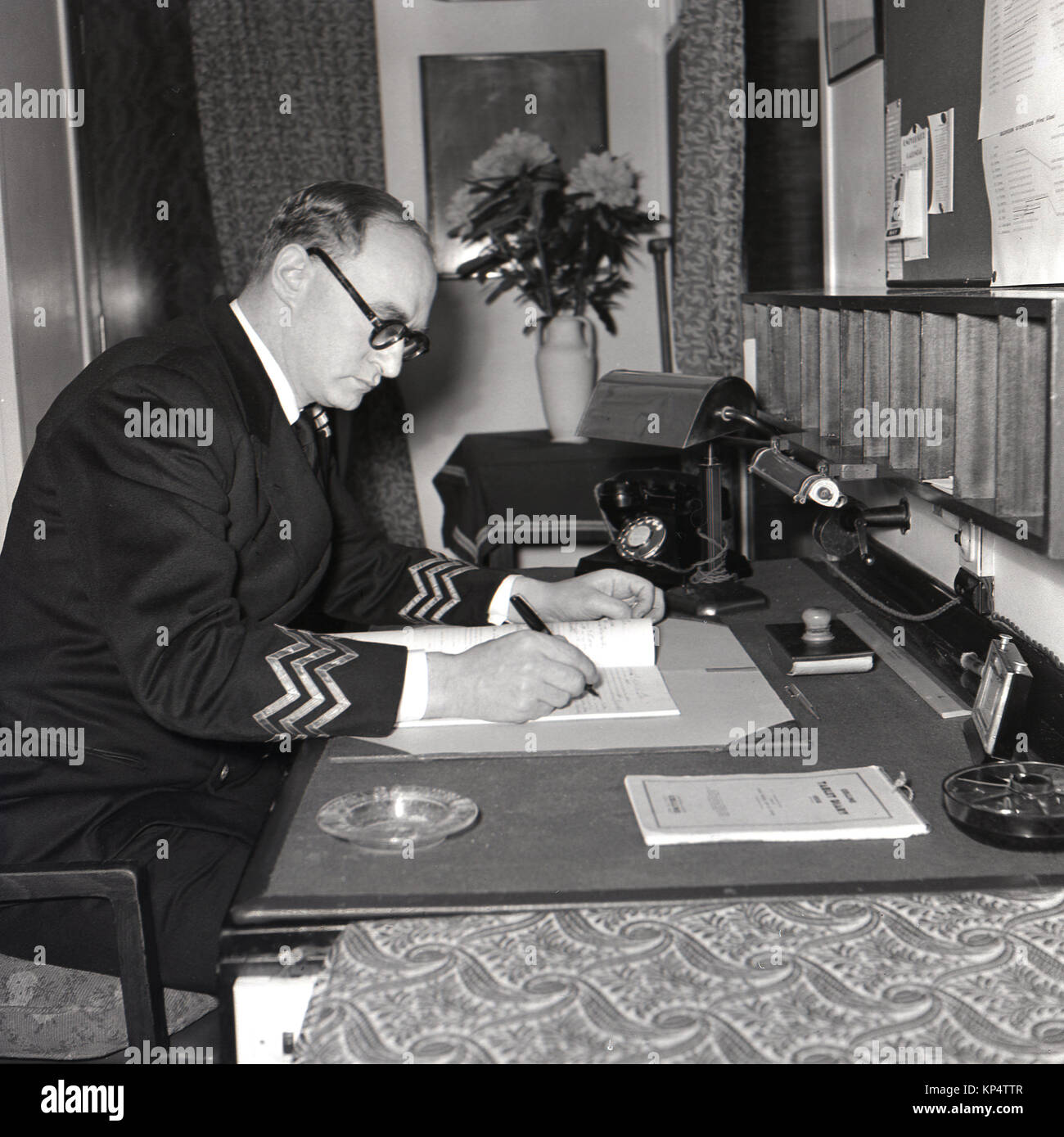 1950s, historical, picture shows a petty officer in uniform sitting working at his desk in a cabin aboard a Union-Castle steam ship. Stock Photo