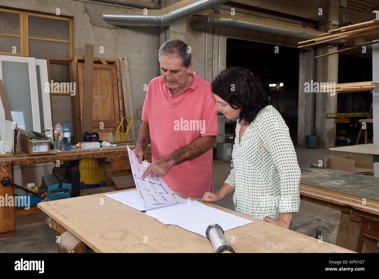 woman looking at the blueprints of a project in the carpenter's ...