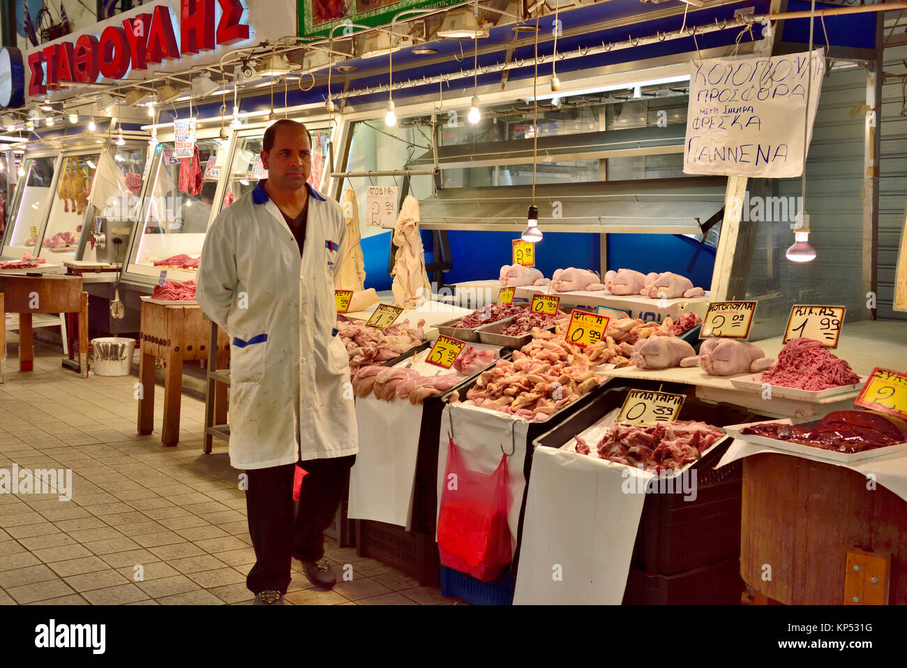 Inside Athens Central Meat Market with butcher by both meat and chicken
