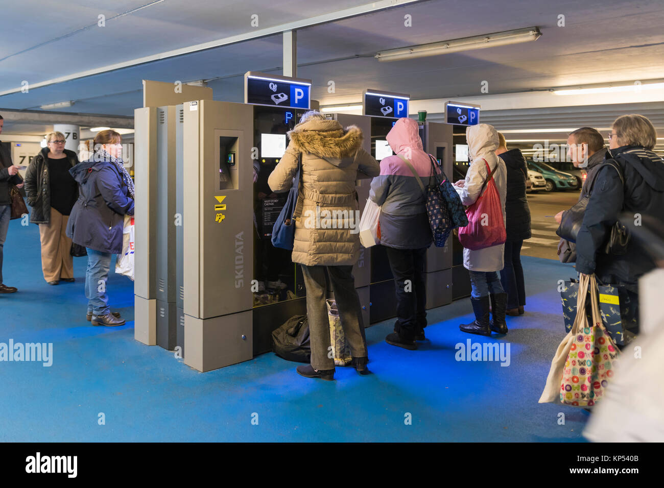 Queue of people in a multi-storey car park in the UK waiting to buy a ticket from parking ticket machines. Stock Photo
