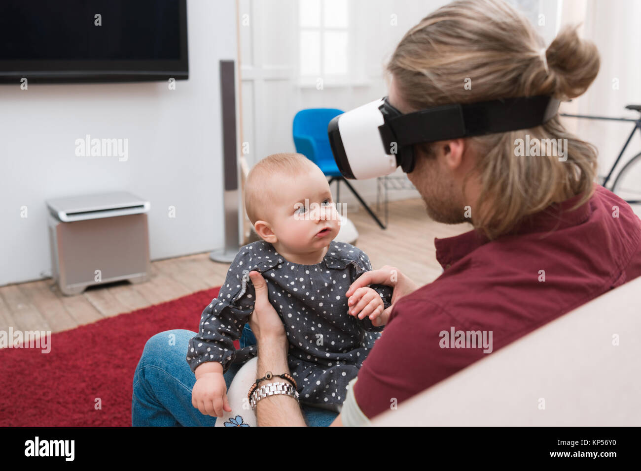 father sitting with his little daughter and using Virtual reality headset Stock Photo