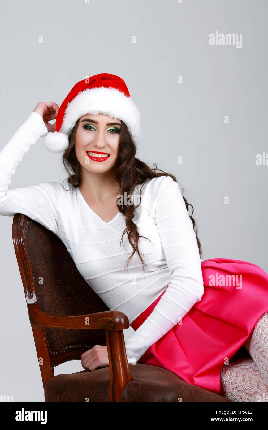 Portrait of young female sitting on chair in santa hat, isolated Stock Photo