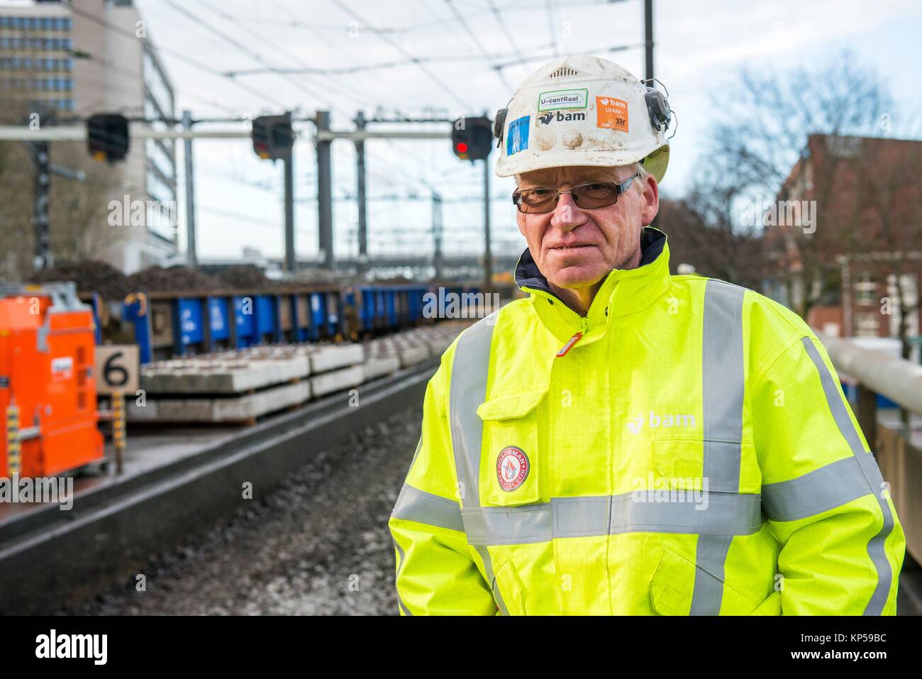 Rotterdam, Netherlands. Senior adult construction worker overseeing the removal of old and used before gravel from a train track in the Stock Photo