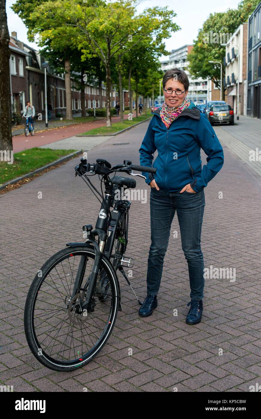 Tilburg, Netherlands. Mature adult caucasian woman and Multiple Sclerosis patient still riding her bike coping with her chronic condition. Stock Photo