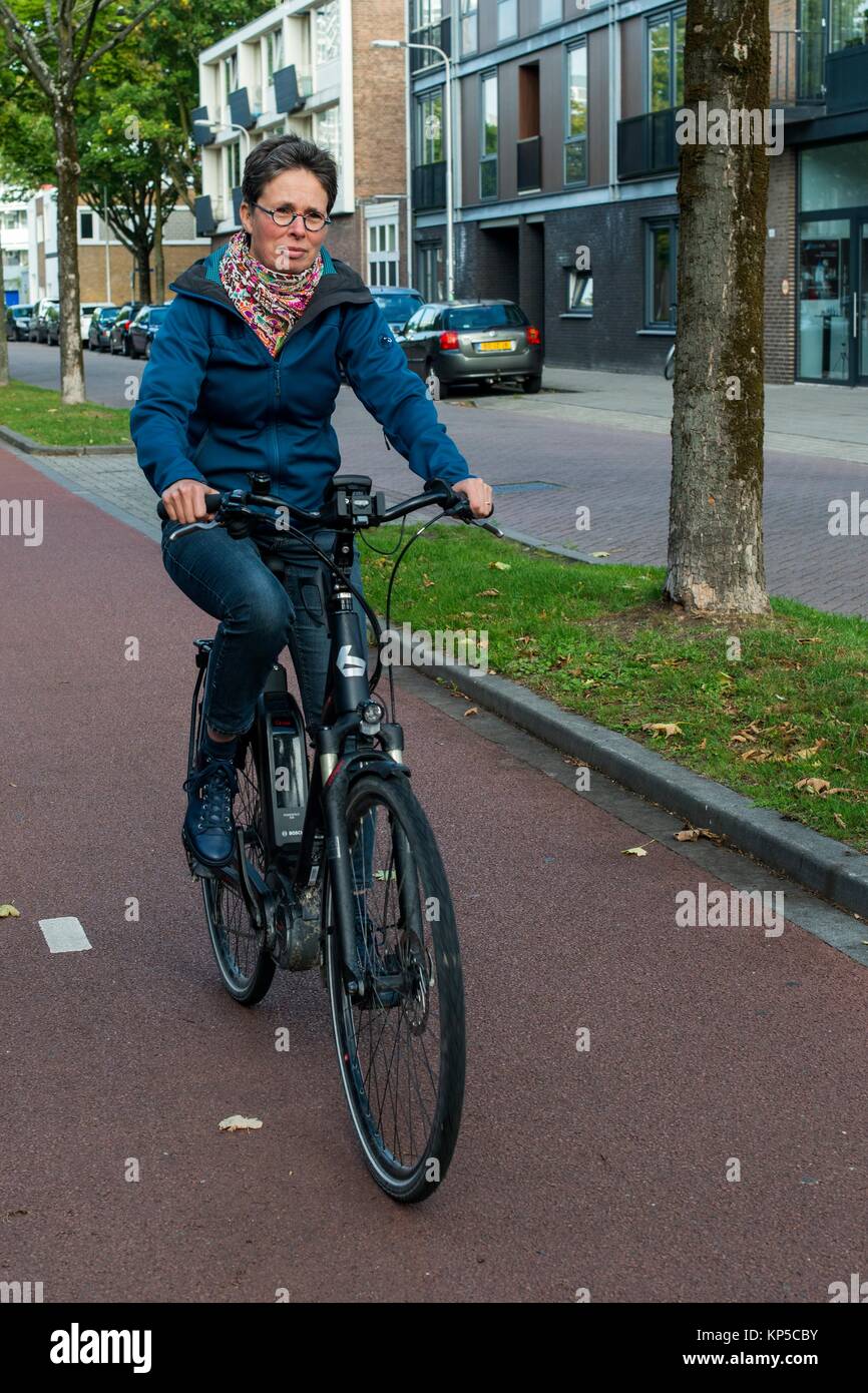 Tilburg, Netherlands. Mature adult caucasian woman and Multiple Sclerosis patient still riding her bike coping with her chronic condition. Stock Photo