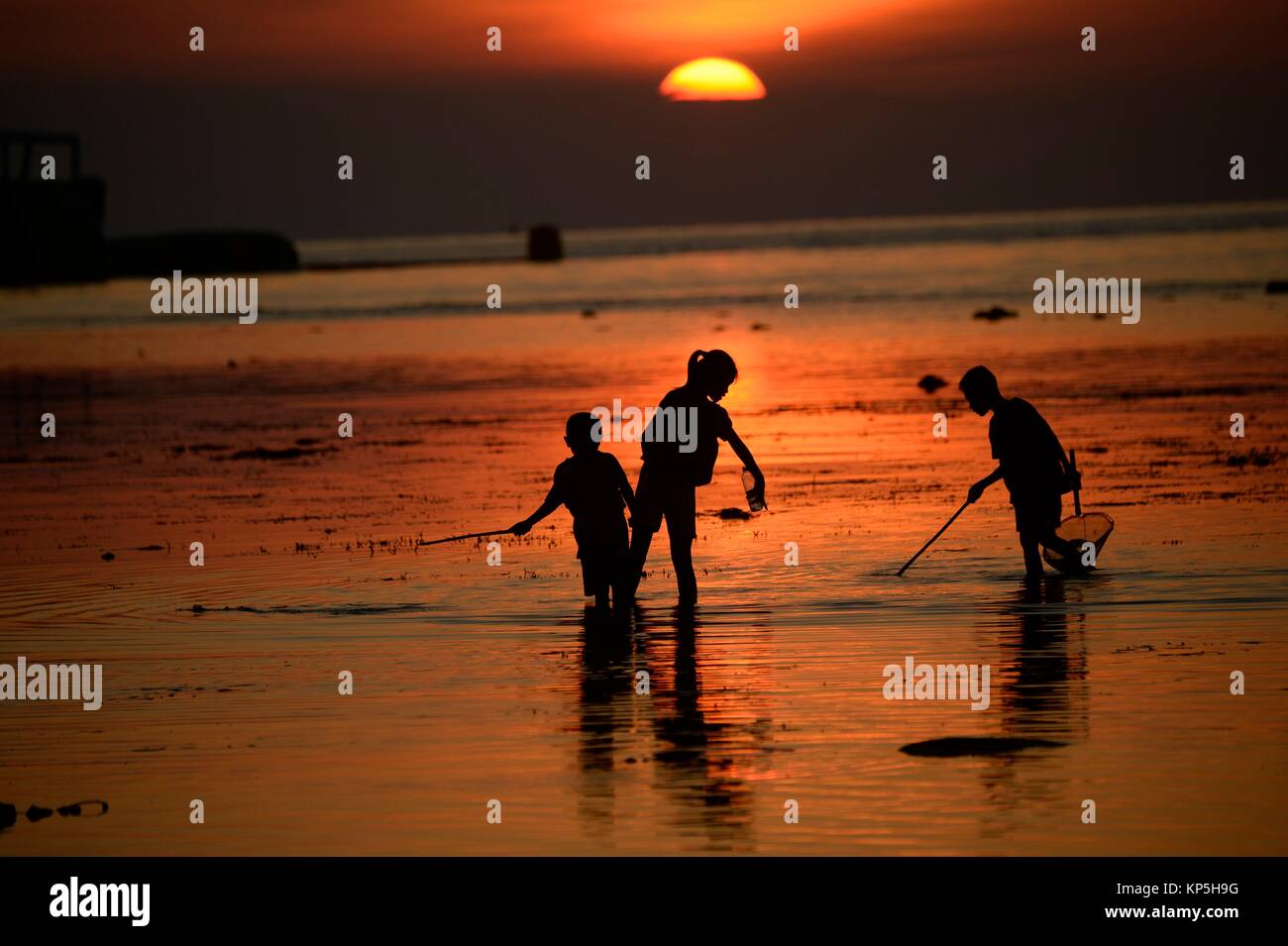 Silhouette of children fishing at sunset in Lovina Beach,Bali island,Indonesia. Stock Photo
