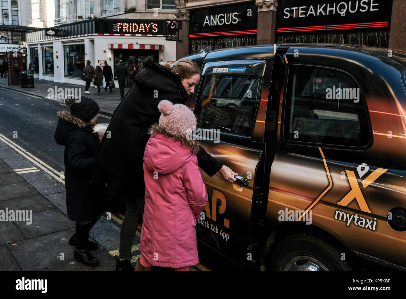 Woman with children hailing a taxi in London, UK Stock Photo