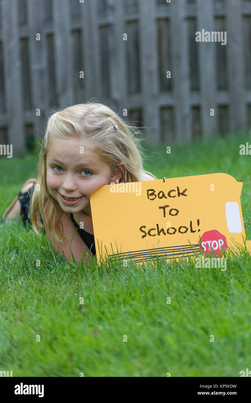 adorable school age girl holding back to school sign for first day of