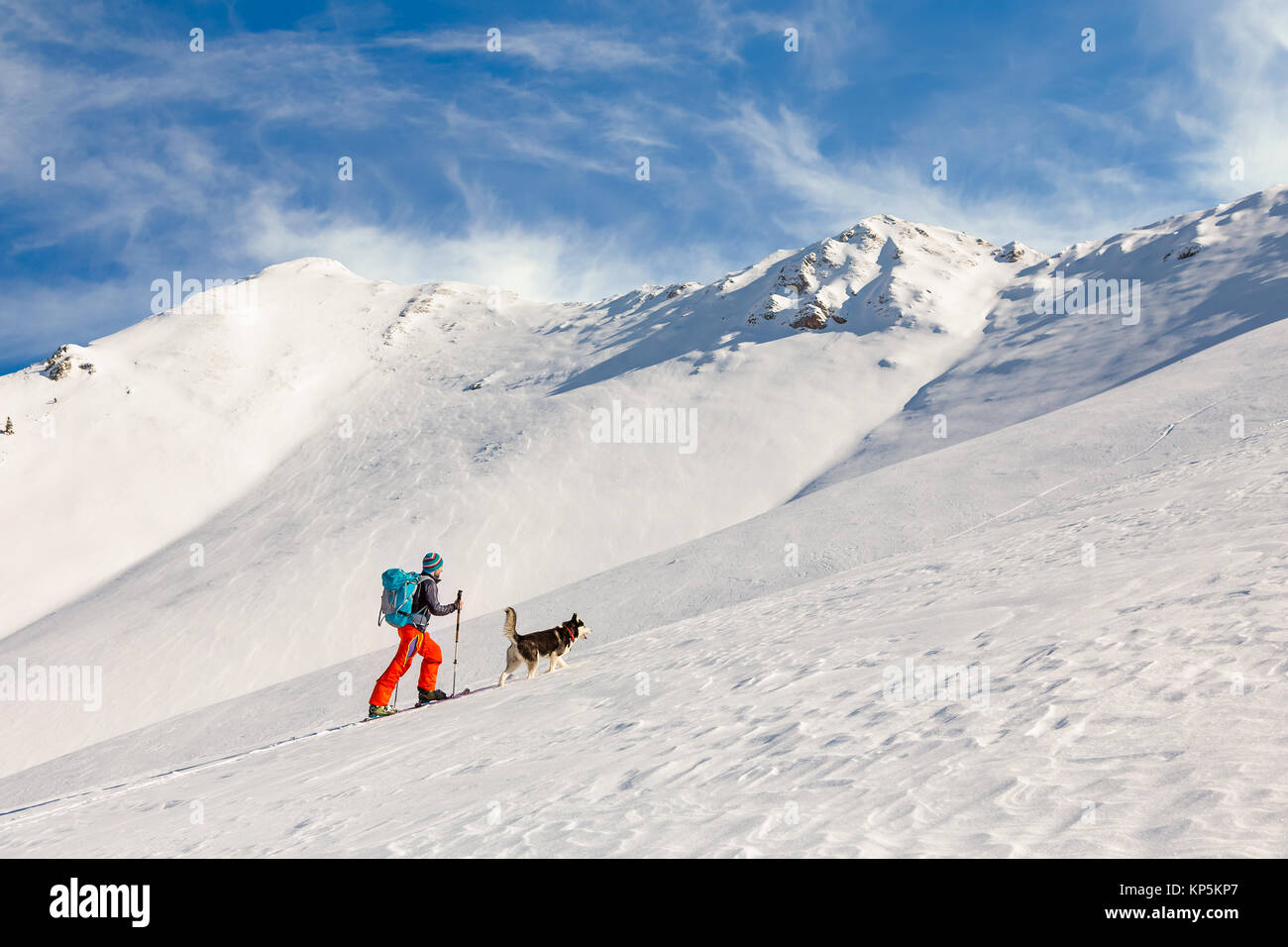 Young man backcountry skiing, going uphill on the mountain, with Stock Photo