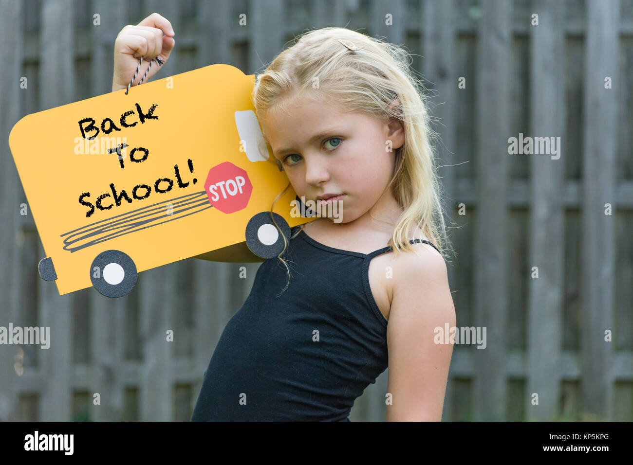adorable school age girl frowning and holding first day of school sign Stock Photo