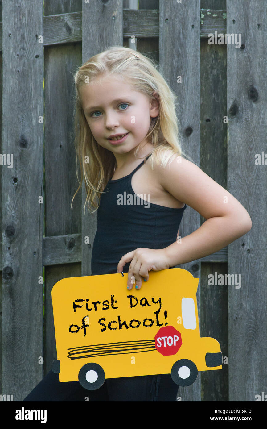 adorable school age girl holding back to school sign for first day of