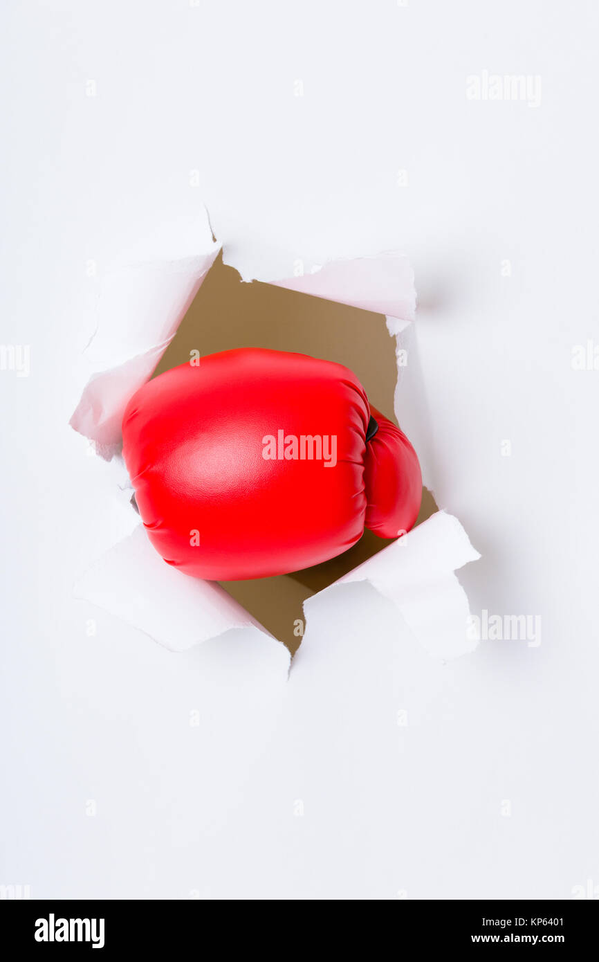 Punching boxing glove though over white paper Stock Photo Alamy