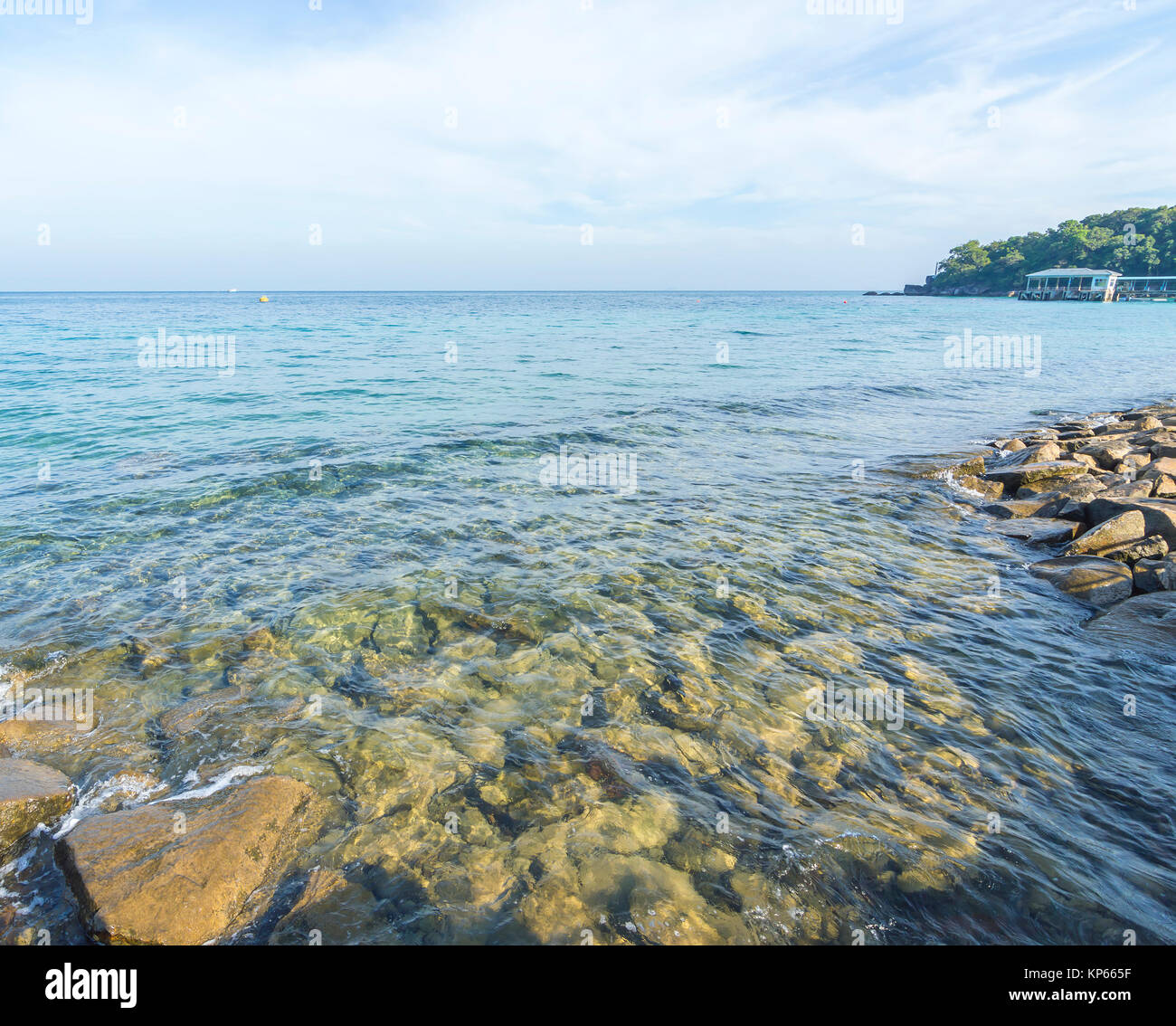 Rock beach with clear water and blue skies Stock Photo - Alamy