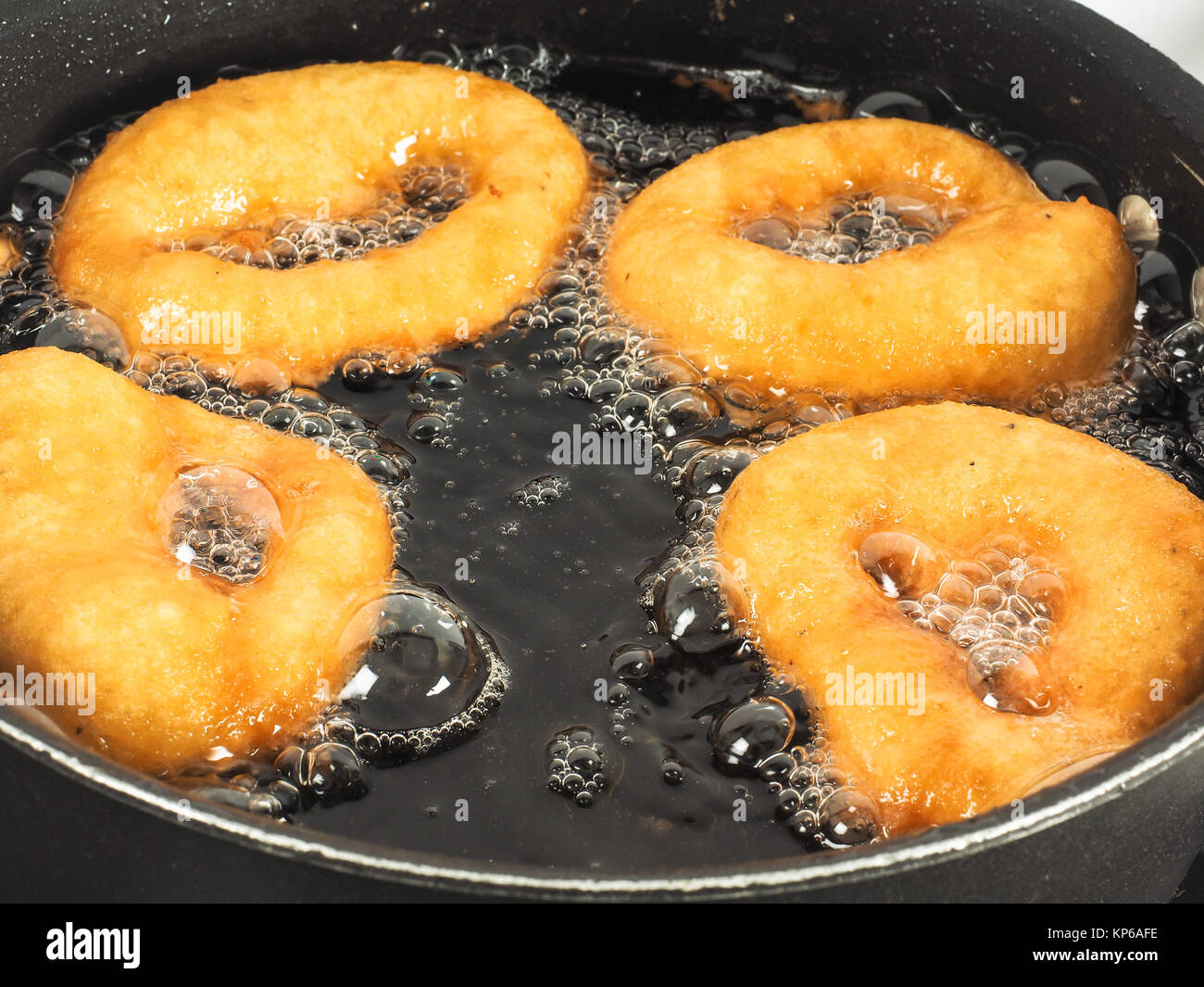 Closeup of donuts cooking in boiling hot oil in kettle Stock Photo Alamy