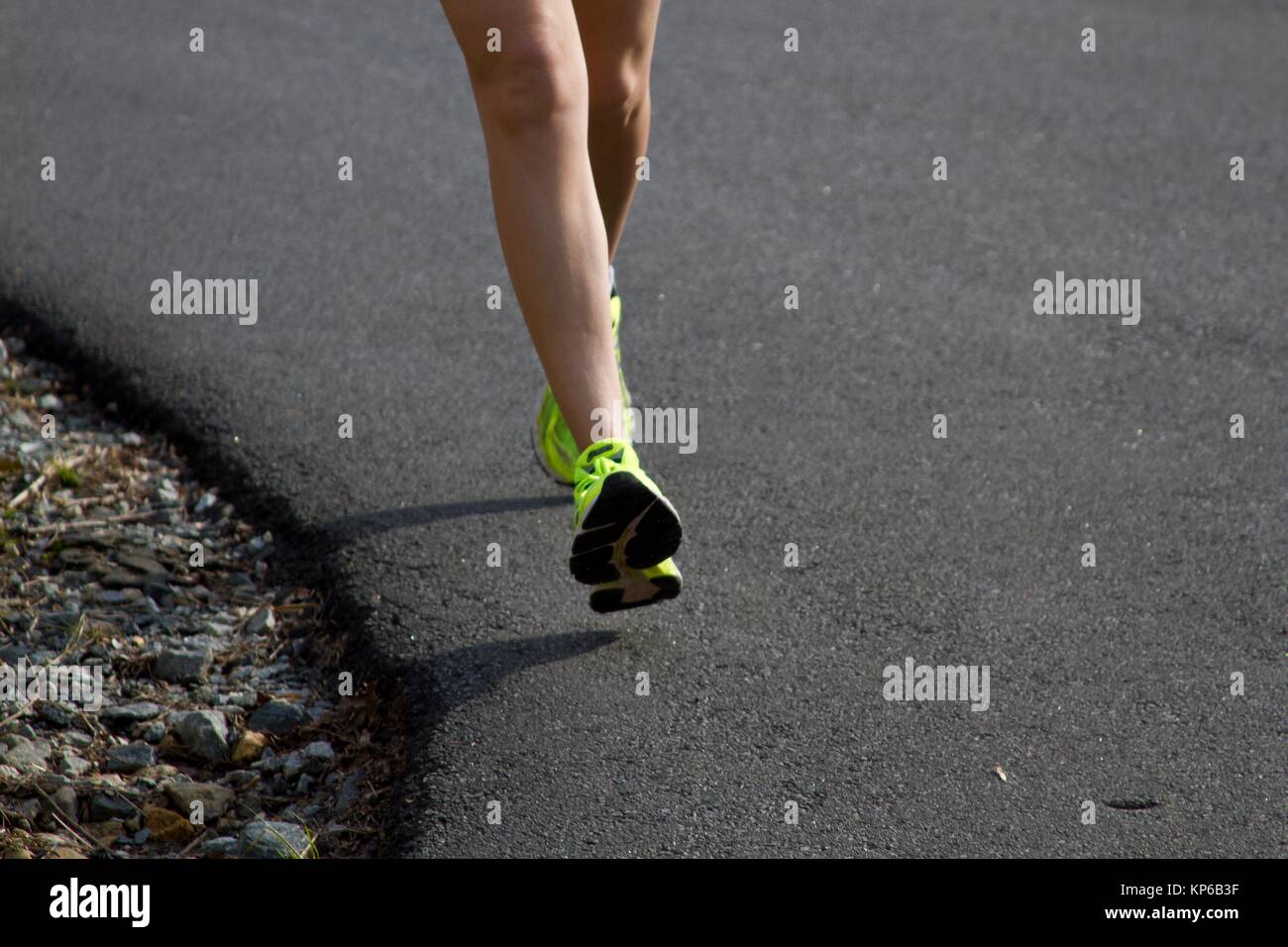 Runner feet running on road closeup on legs and feet and on yellow shoe
