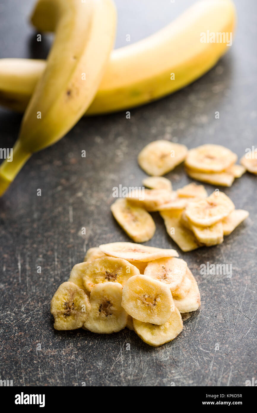 Dried banana chips on old kitchen table. Stock Photo