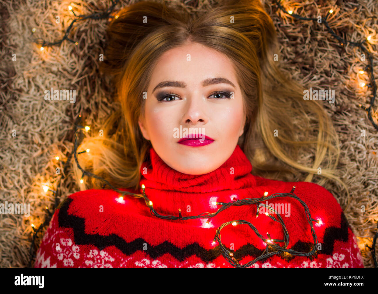 Beautiful girl with festive lights lying on the carpet Stock Photo