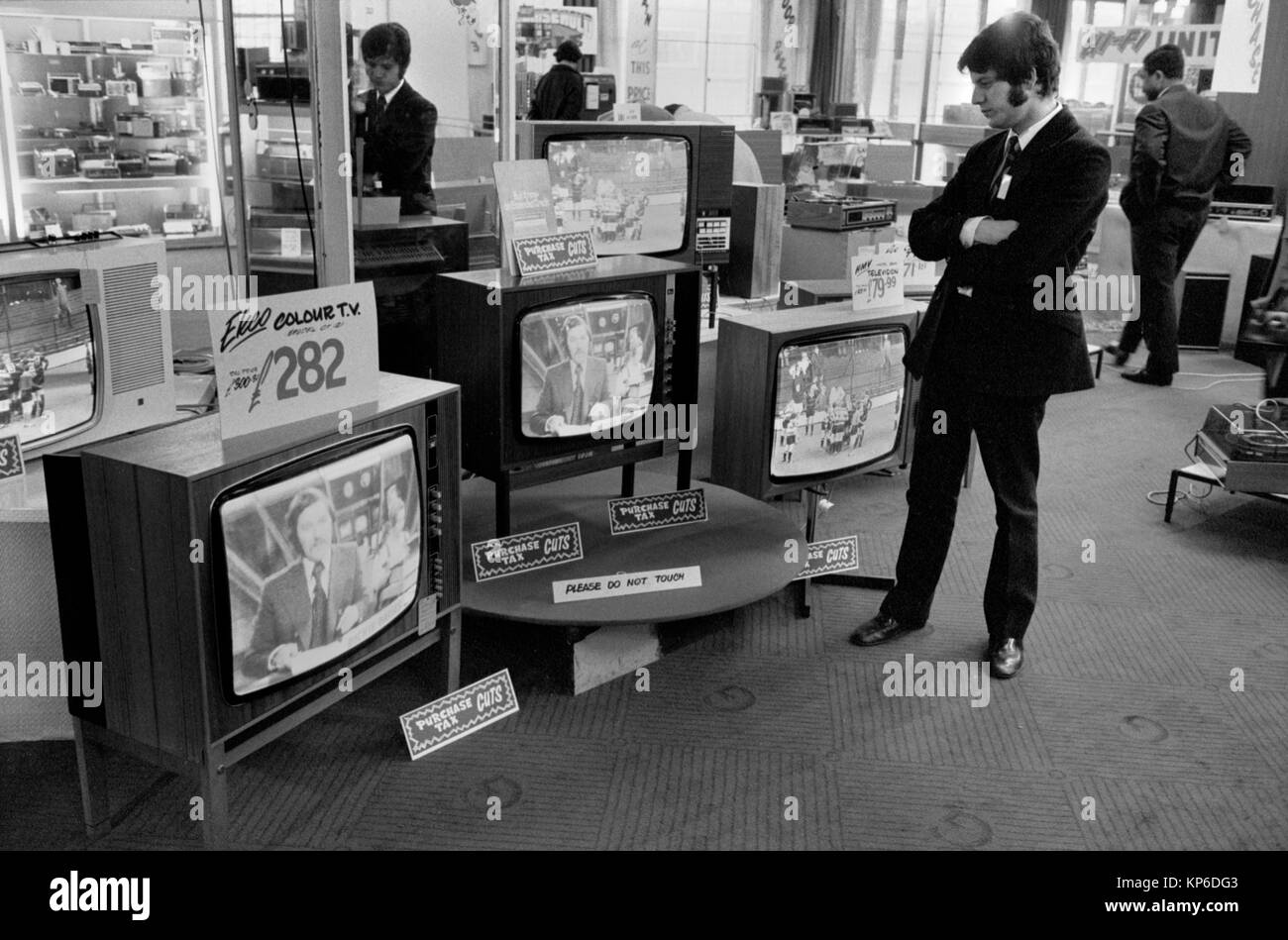 1970s Uk department store selling televisions. Signs say 'Purchase Tax Cuts'. Sales assistant in retail London 70s  watching TV waiting for a customer. Dickie Davies ITV World of Sport TV presenter is on the telly. 1972 HOMER SYKES Stock Photo