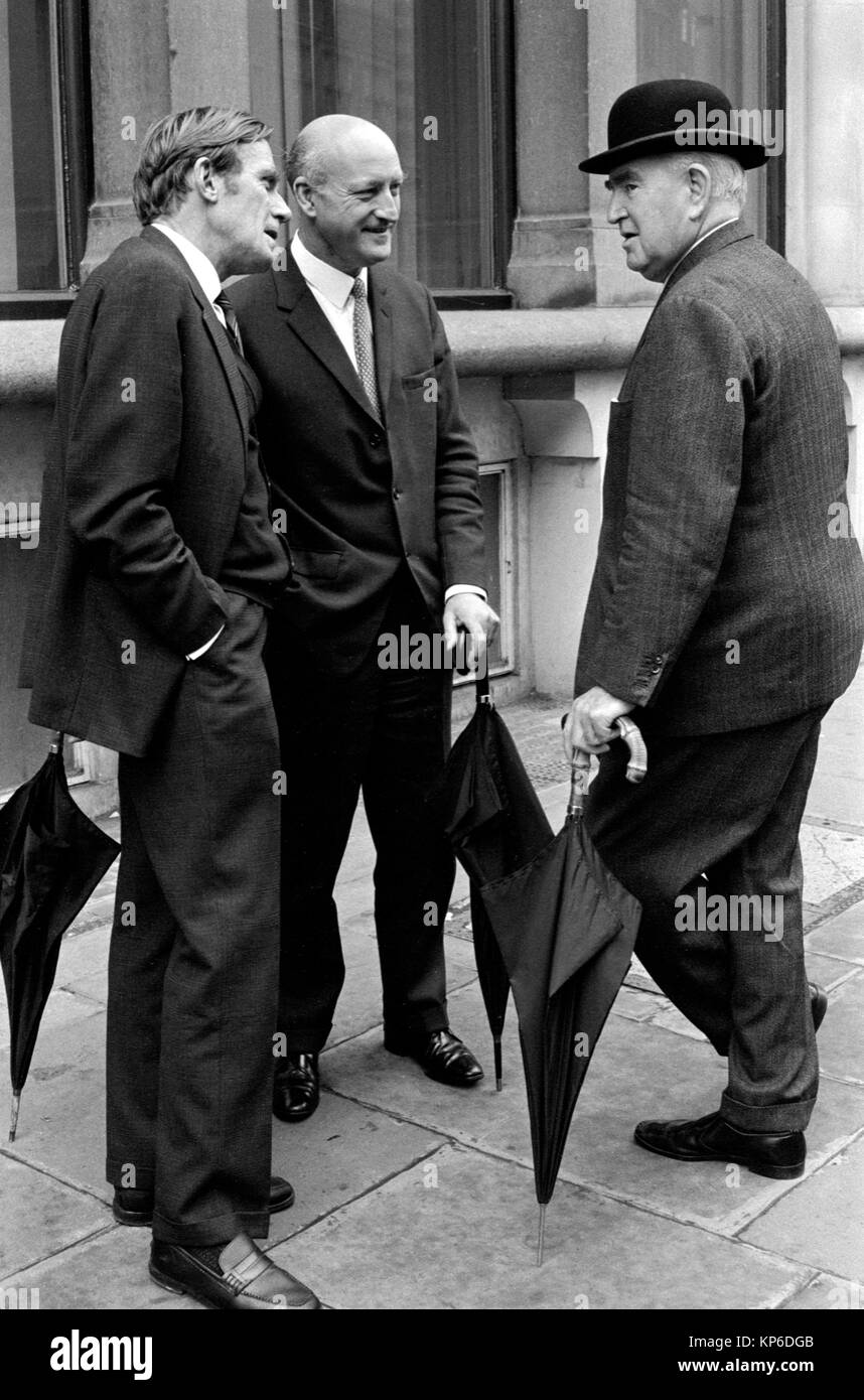 1970s City of London UK men wearing bowler hat and carrying rolled umbrellas dress code for the 70s. Middle aged business managers office workers talking together in the street. England HOMER SYKES