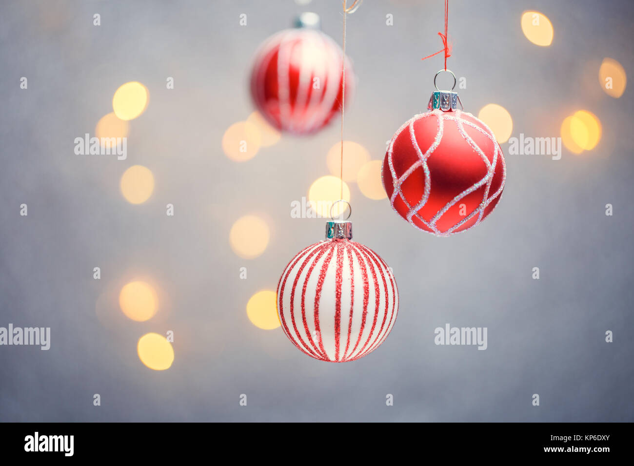 Photo of three Christmas tree red balls with pattern on gray background with hot lights. Stock Photo