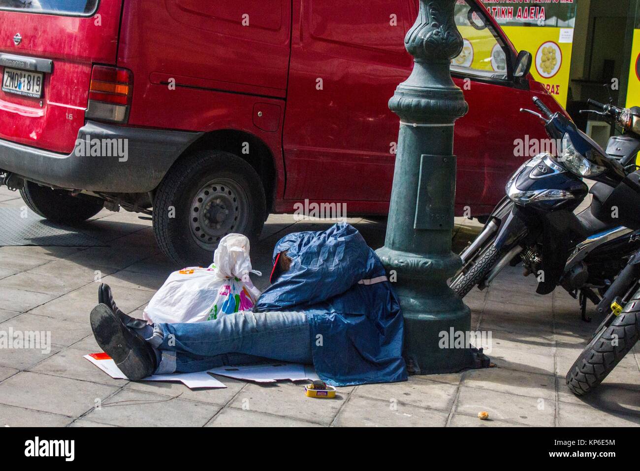 A non recognizable caucasian homeless man in his 50´s and his blue outfit  sleeping at the feet of a lamp post in Athens, Greece, Europe Stock Photo -  Alamy