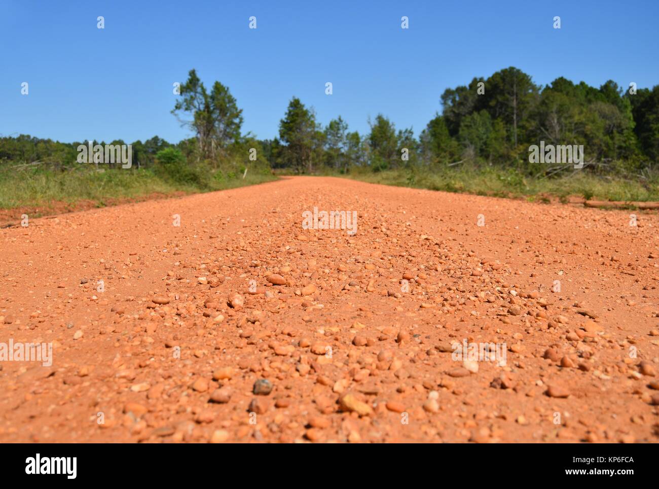 A generic red gravel road with no people under a bright blue sky in Alabama, USA Stock Photo