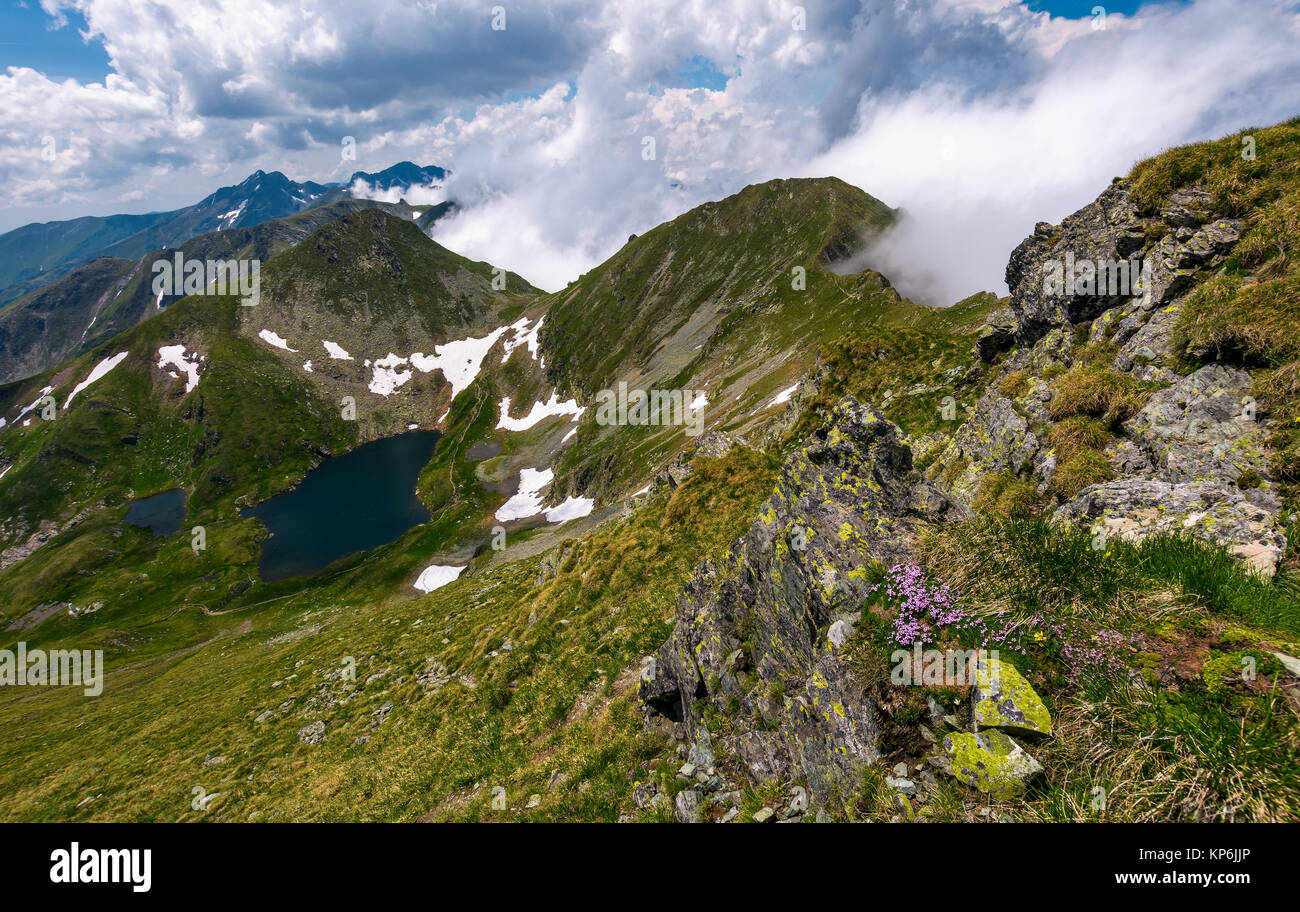 edge of steep slope on rocky hillside in cloudy weather. dramatic scenery with snow near glacier in Fagaras mountains Stock Photo