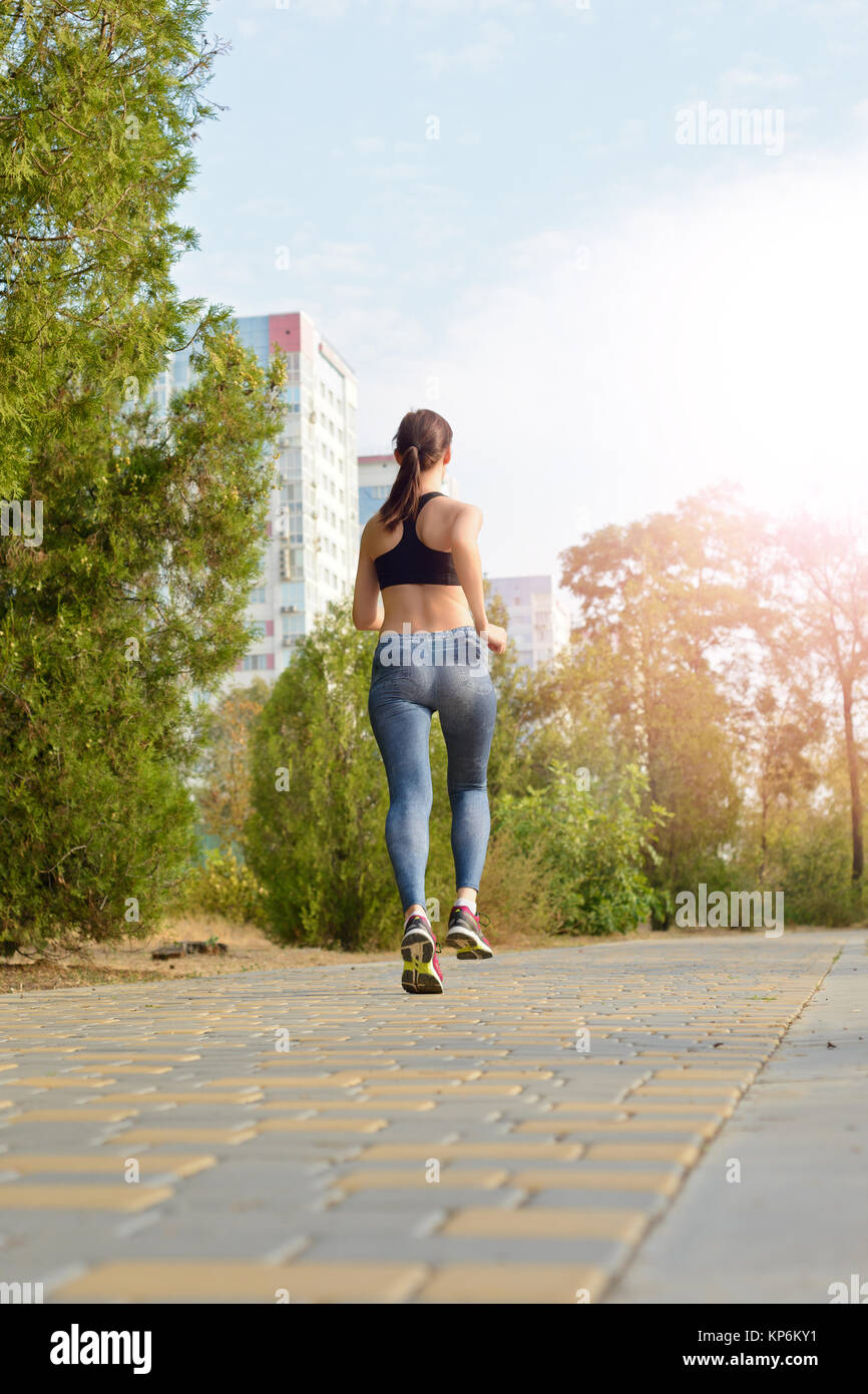 A running girl, a girl running along the pathway the background of high-rise buildings Stock Photo