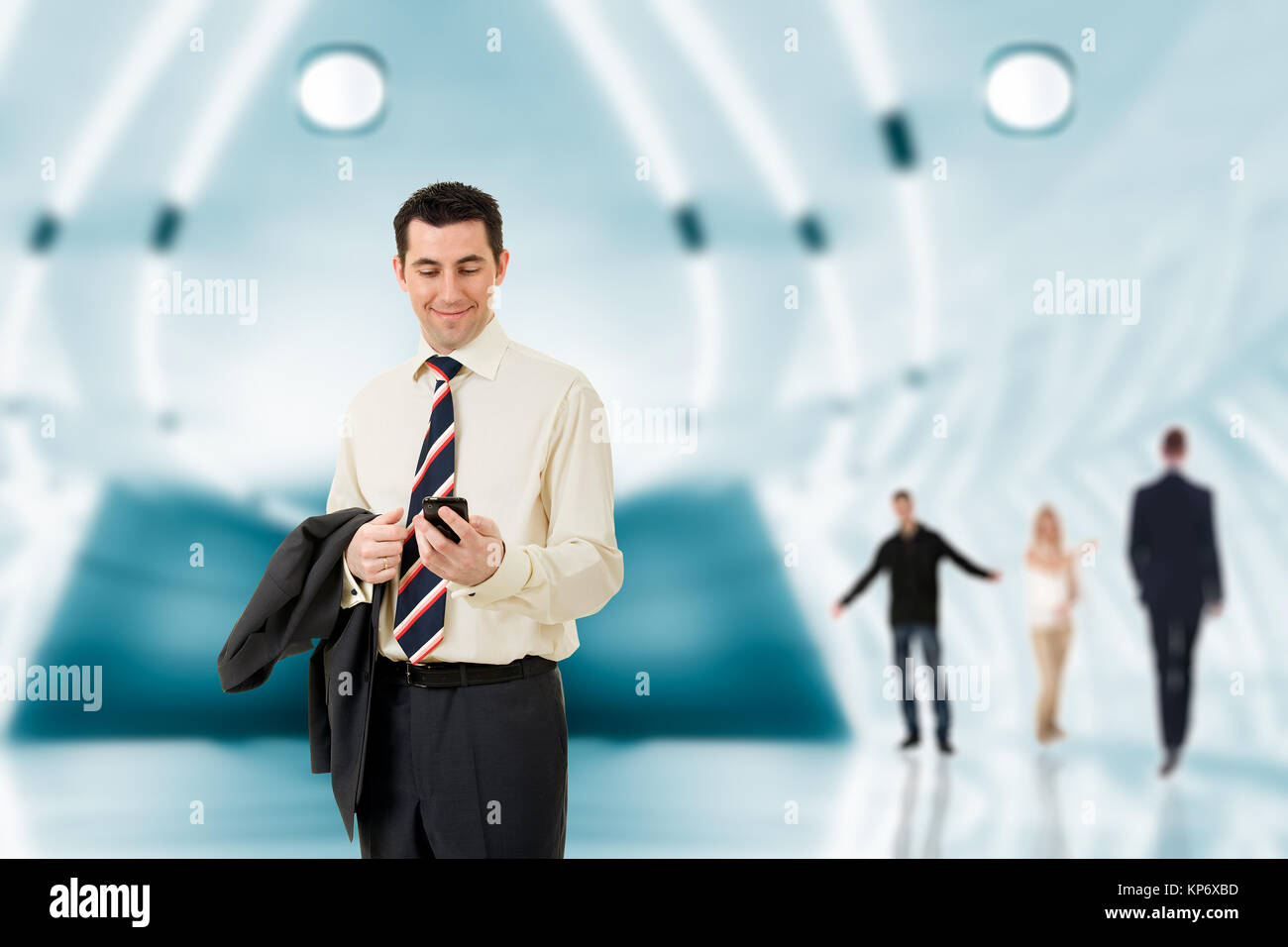 Businessman in a modern hall looking at his mobile phone and smiling ...