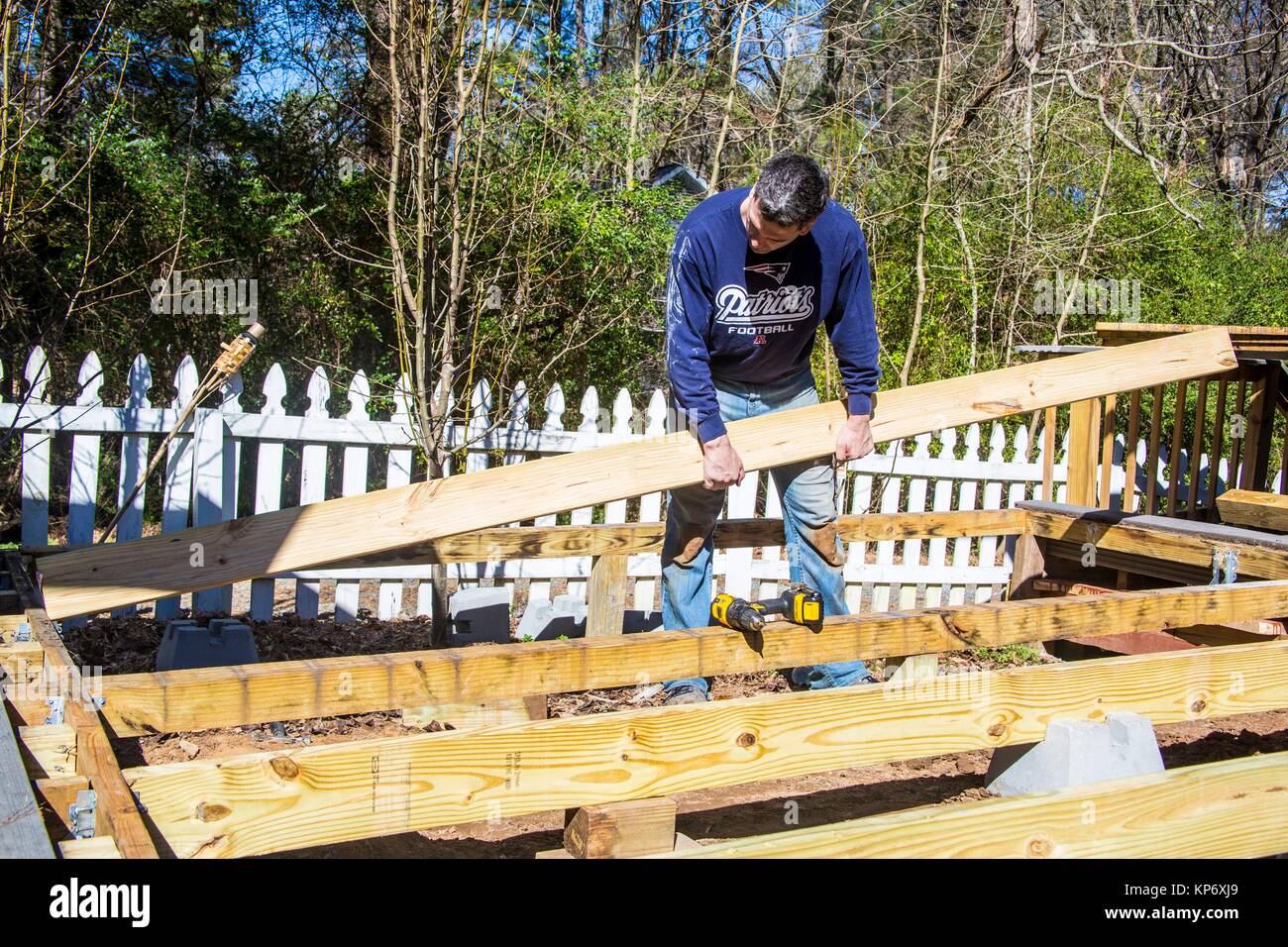 caucasian man building a deck, lifting concrete and wood planks Stock