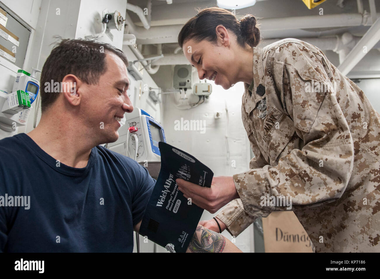 Hospital Corpsman 1st Class Tonya Jury, a native of Golden, Colo., assigned to the health services department aboard the amphibious assault ship USS America (LHA 6), checks the blood pressure of Chief Hospital Corpsman Andy Warren, a native of Thomasville, Ga., in the main battle dressing station. America is the flagship for the America Amphibious Ready Group and, with the embarked 15th Marine Expeditionary Unit, is deployed to the U.S. 5th Fleet area of operations in support of maritime security operations to reassure allies and partners and preserve the freedom of navigation and the free flo Stock Photo