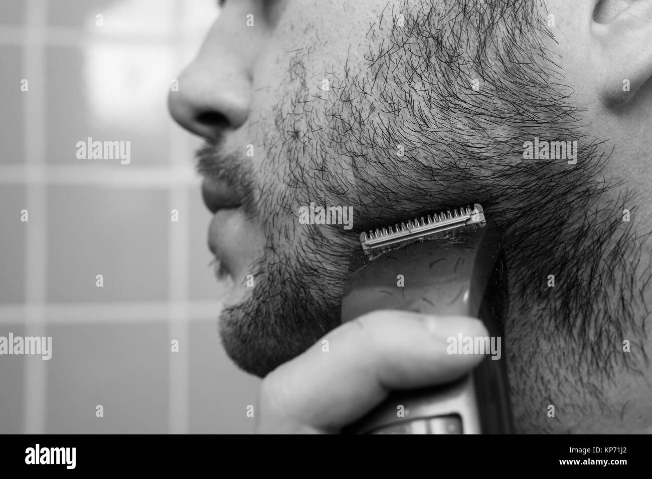 Portrait of young man shaving with trimmer Stock Photo Alamy