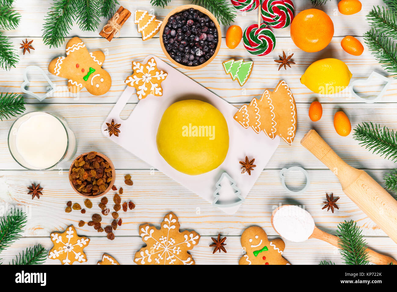 Cooking Christmas gingerbread cookies with the ingredients, dough, candy and winter spices decorating for new year celebration on white wooden table.  Stock Photo