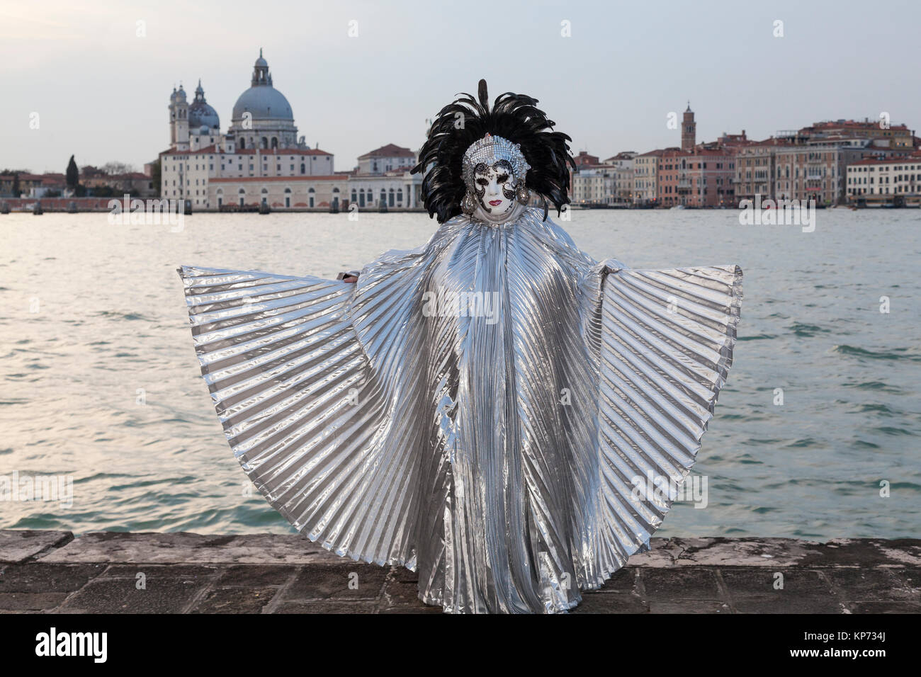 Venice Carnival 2017, Veneto, Italy woman with extended silver wings and Basilica di Santa Maria della Salute at sunset Stock Photo