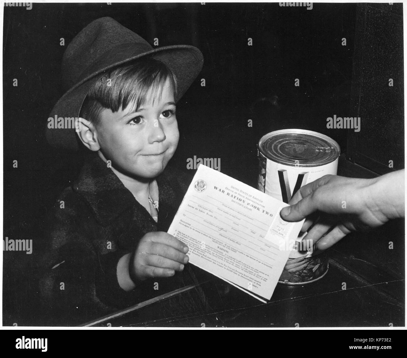 An eager school boy gets his first experience in using War Ration Book Two. With many parents engaged in war work, children are being taught the facts of point rationing for helping out in family marketing., ca. 02/1943 Stock Photo