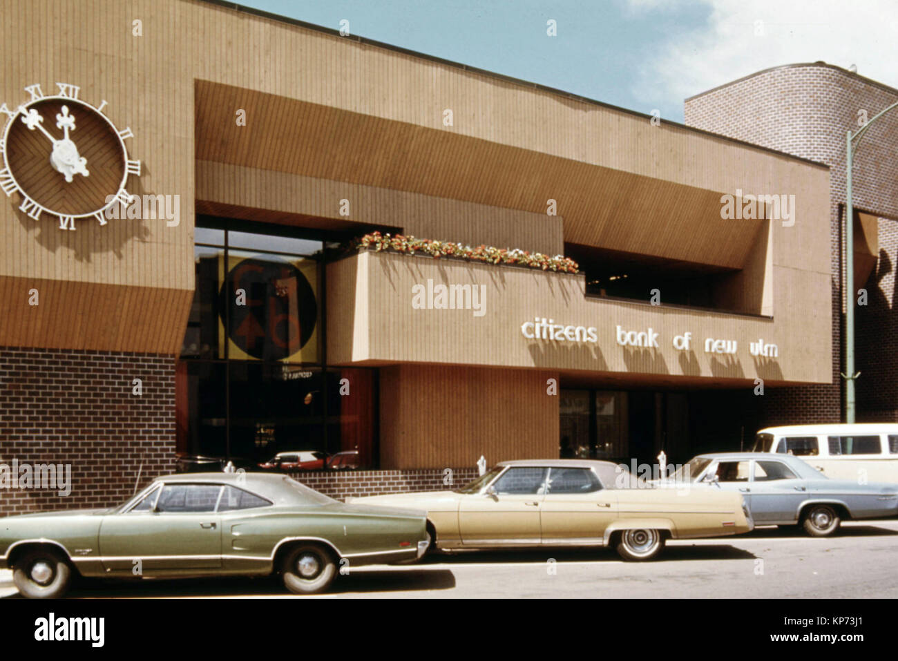 Automobiles parked in front of a bank building in downtown New Ulm, MN