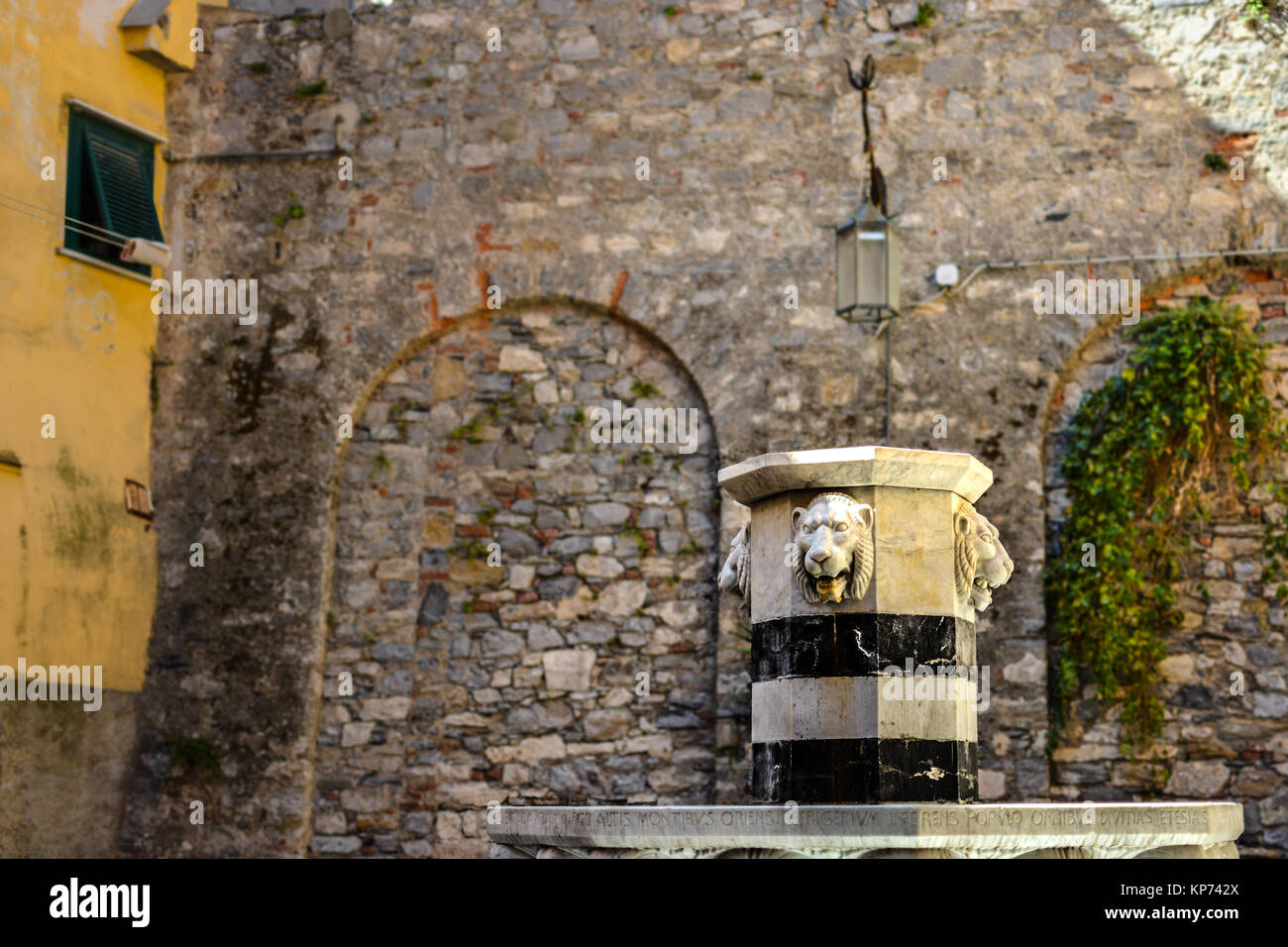 A fountain with stone lion heads in small courtyard inside the walled section of Portovenere Italy Stock Photo