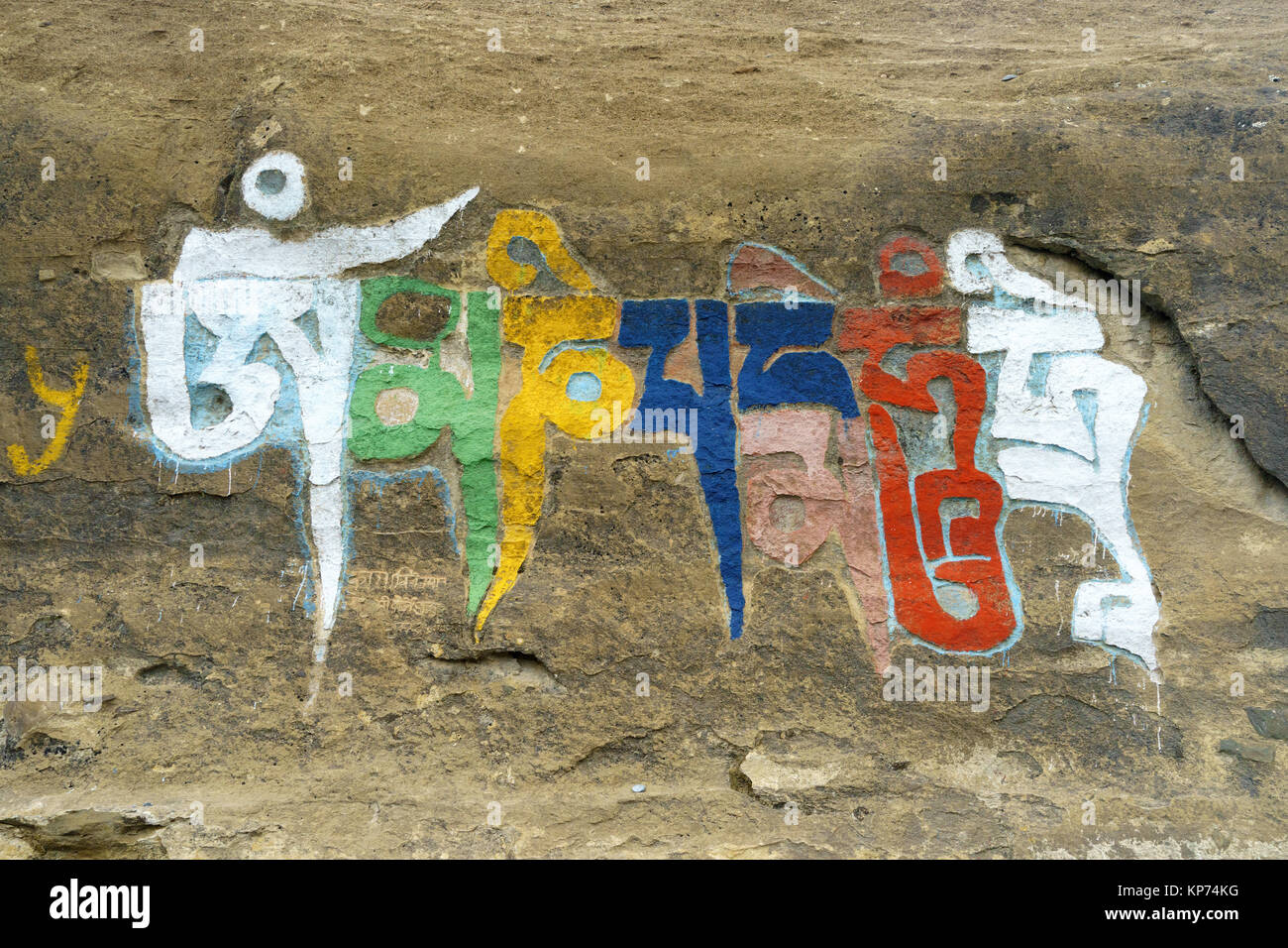 Om mani padme hum Buddhist mantra painted in bright colors on a rock. Upper Mustang region, Nepal. Stock Photo