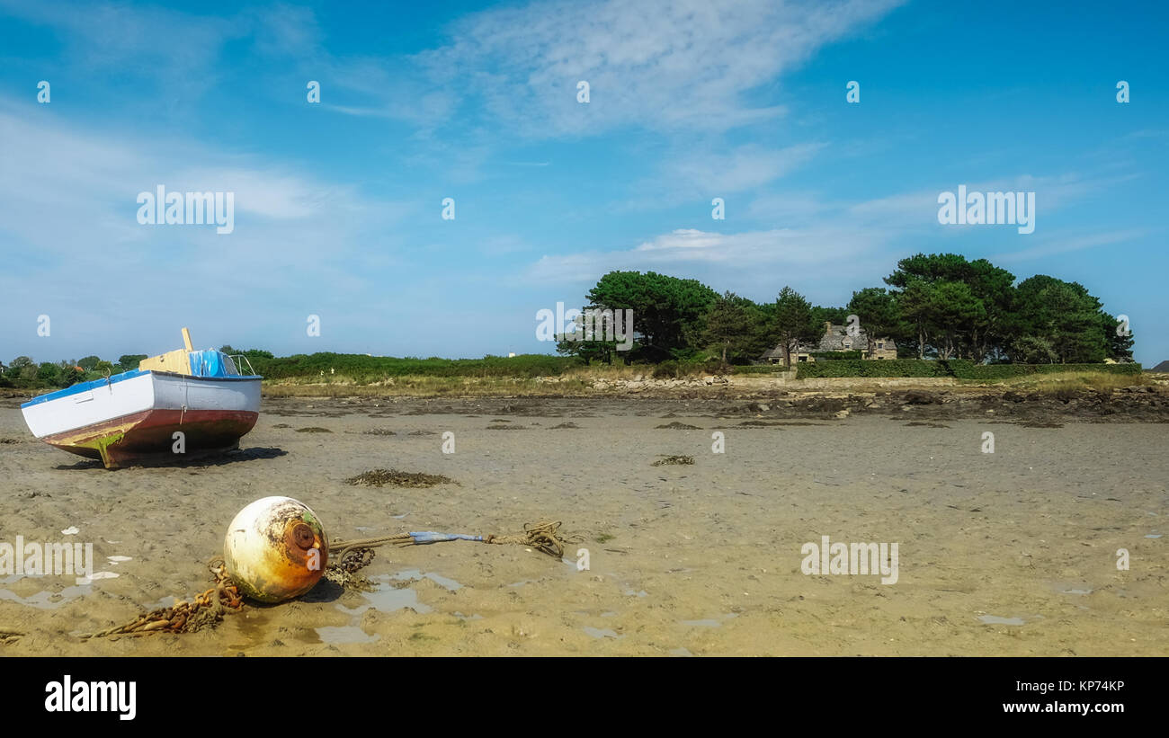Fisher boat resting in the sand near old stone house on an island Stock Photo