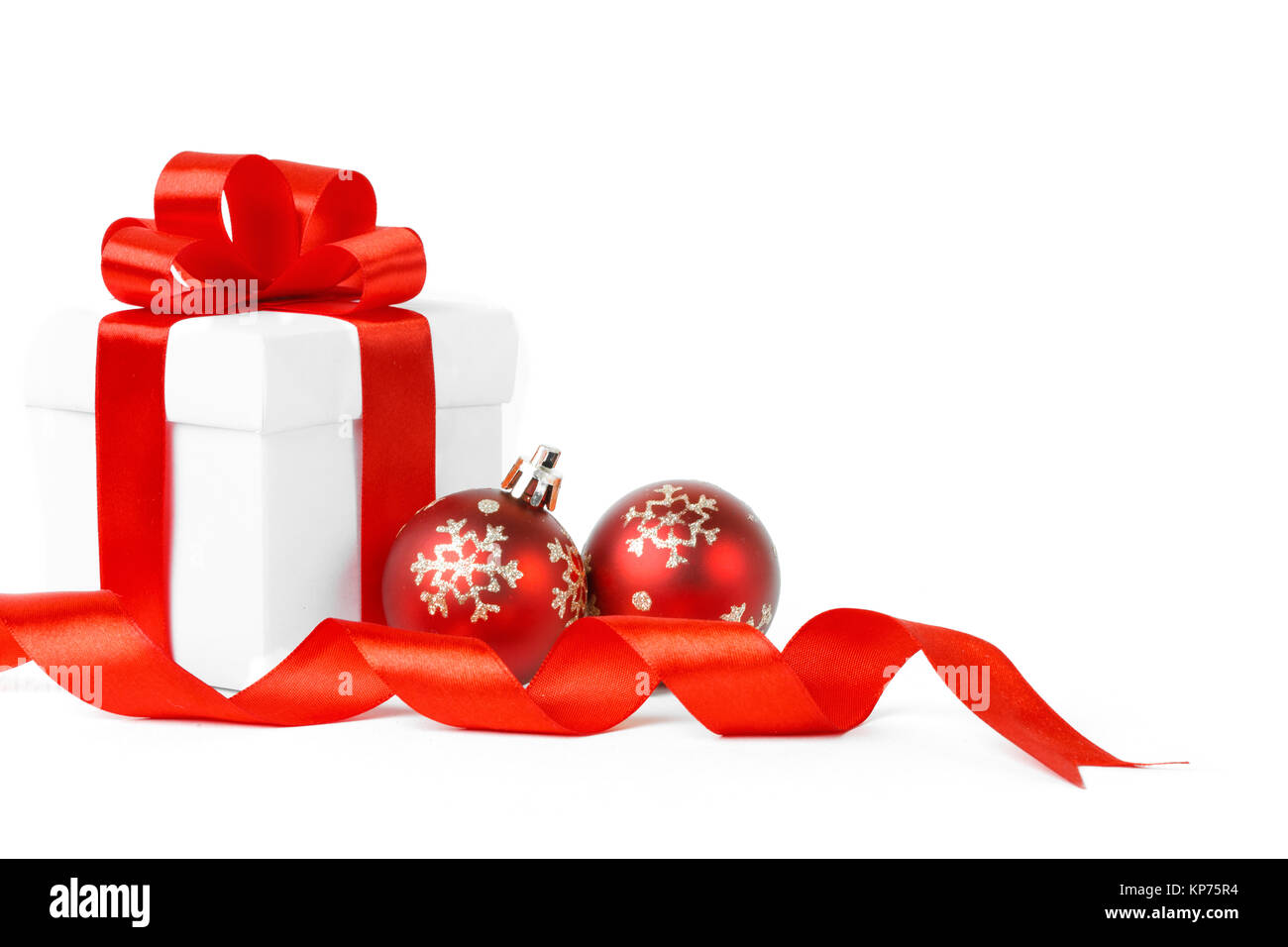 White gift box with red ribbon bow and christmas balls around, isolated ...