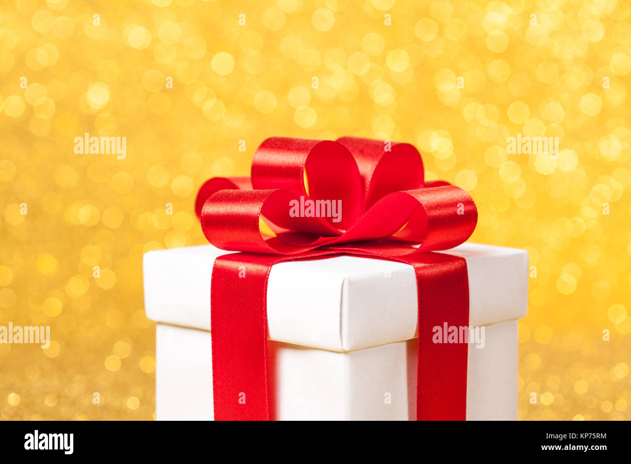 White gift box with red ribbon bow on gold glitter background Stock ...