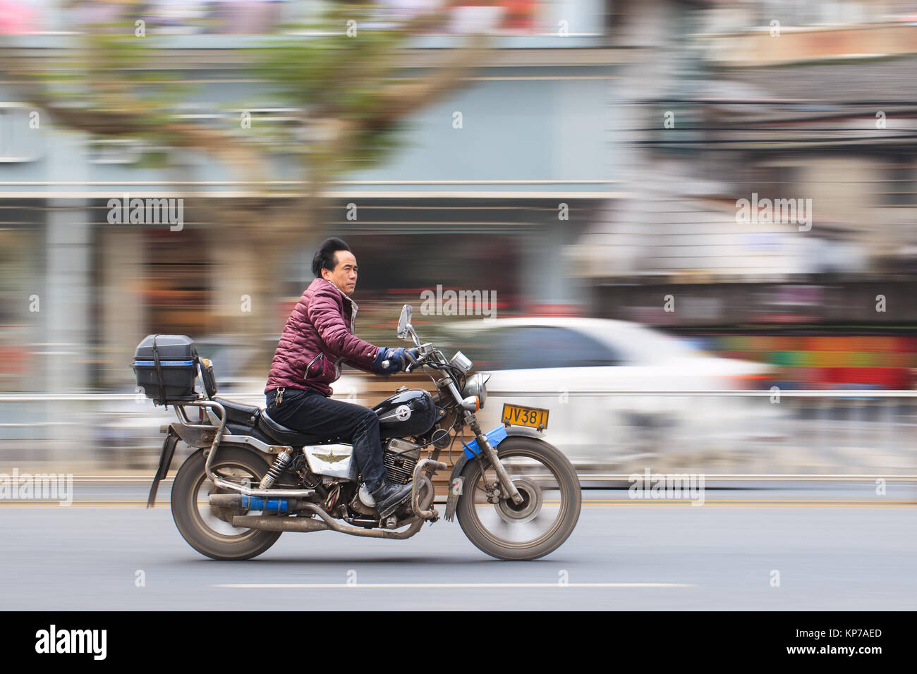 YIWU-CHINA-JAN. 15, 2016. Chinese man on motorcycle on speed. Large cities, like Beijing and Guangzhou, banned motorcycles from urban areas. Stock Photo
