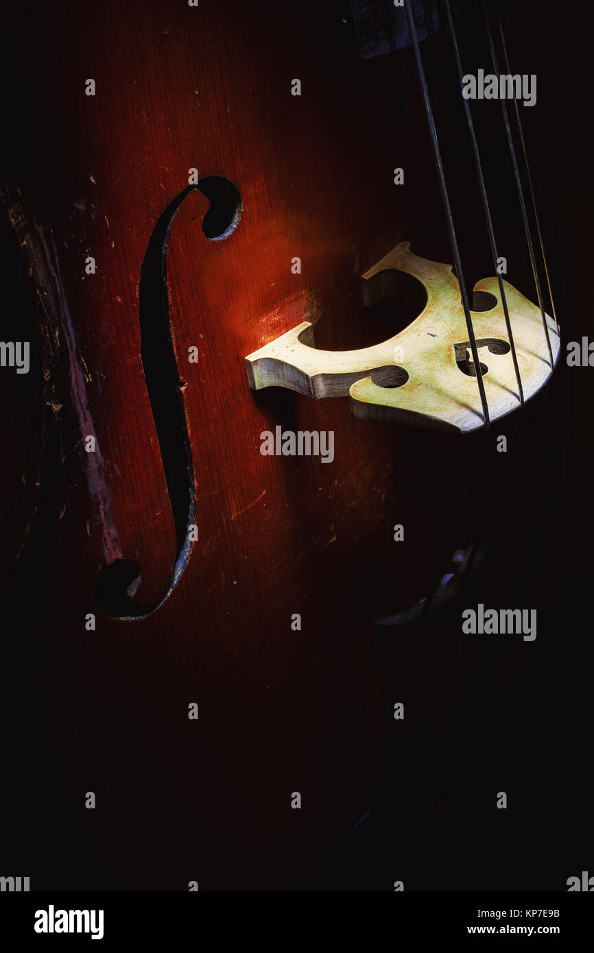 Illuminated middle part of an old and dusty upright bass. Stock Photo