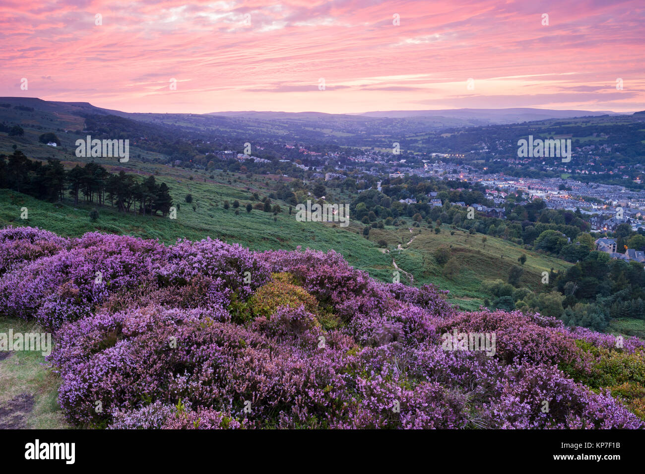 Deep pink sunset sky & high view from picturesque Ilkley Moor over town nestling in valley (purple heather) - Ilkley, Wharfedale, Yorkshire, GB, UK Stock Photo