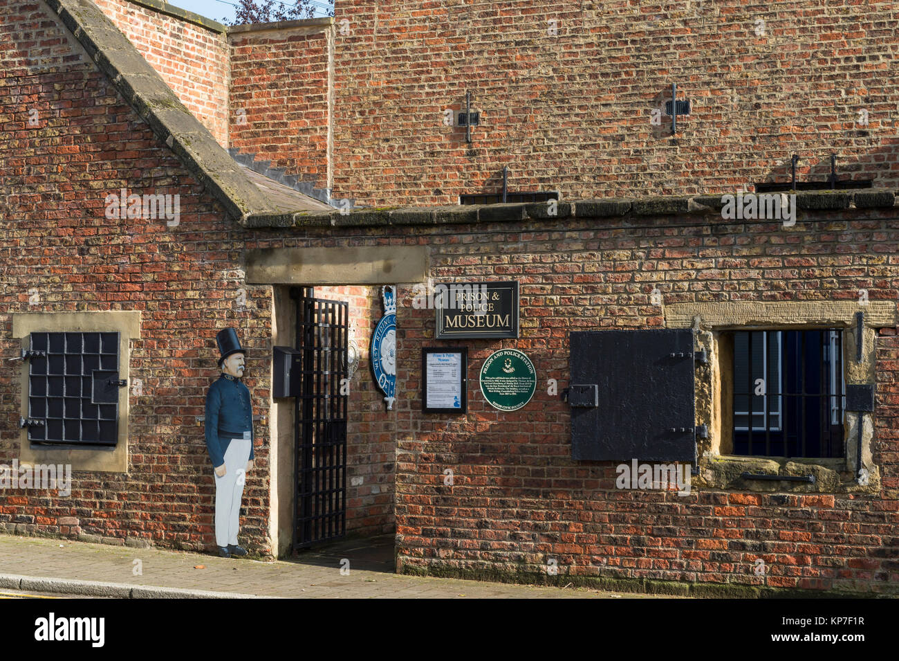View of entrance, barred windows, shutter & signs on exterior of historic jail, now Prison and Police Museum - Ripon, North Yorkshire, England, UK. Stock Photo