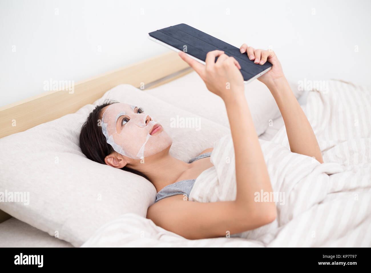 Asian Woman using the tablet pc and facial mask Stock Photo Alamy