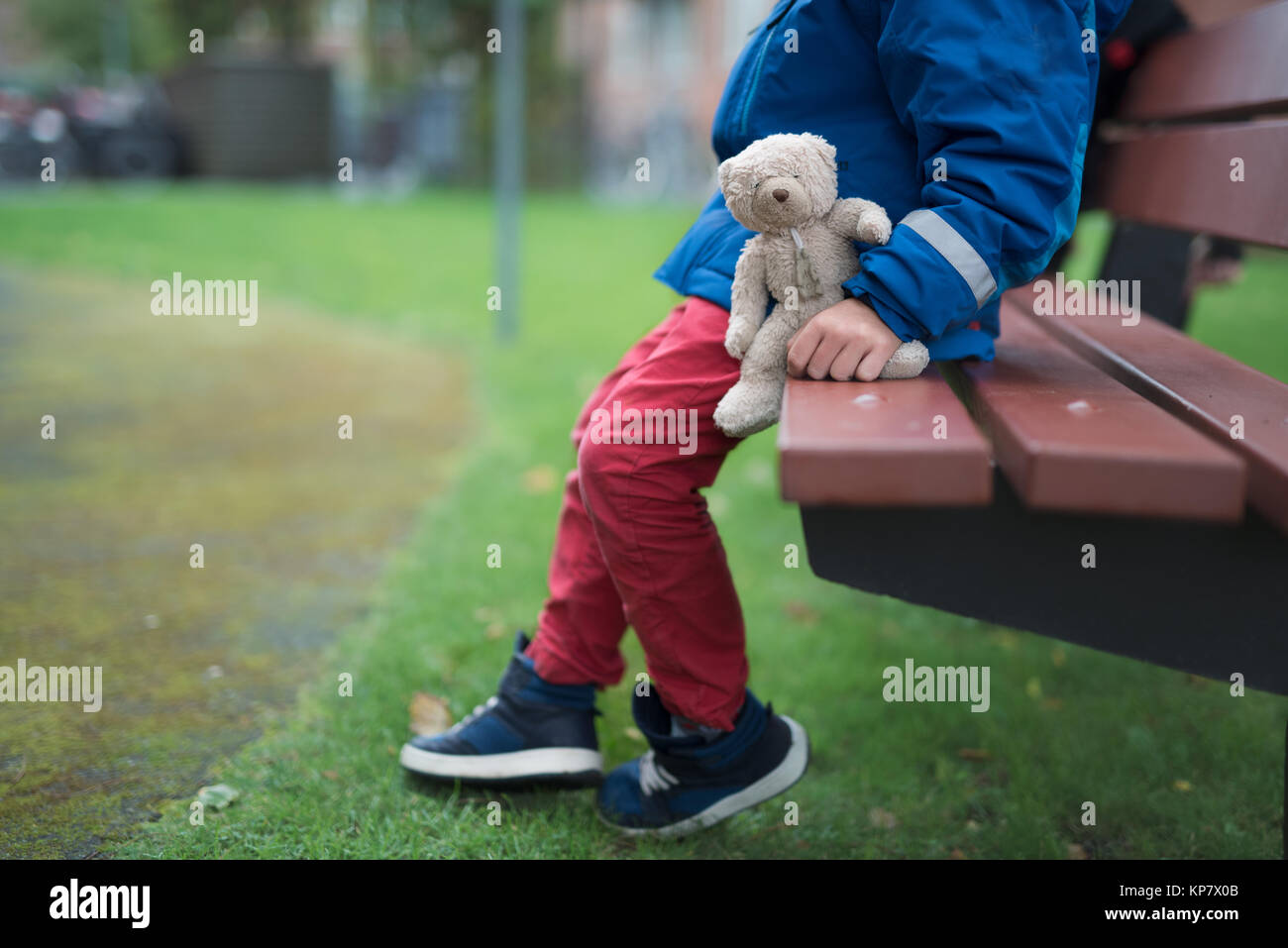 Boy sitting alone with his teddy bear in a park Stock Photo - Alamy