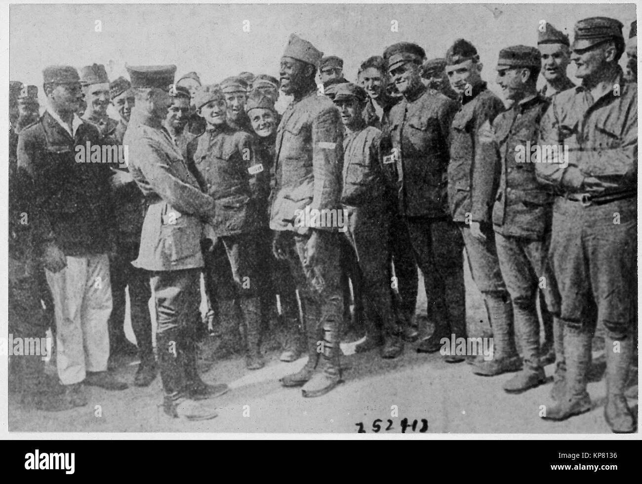 Americans in German prison camp. A group of American prisoners in a German prison camp listening attentively while a jovial [African American] fighter relates an episode of war life to a German officer. Stock Photo