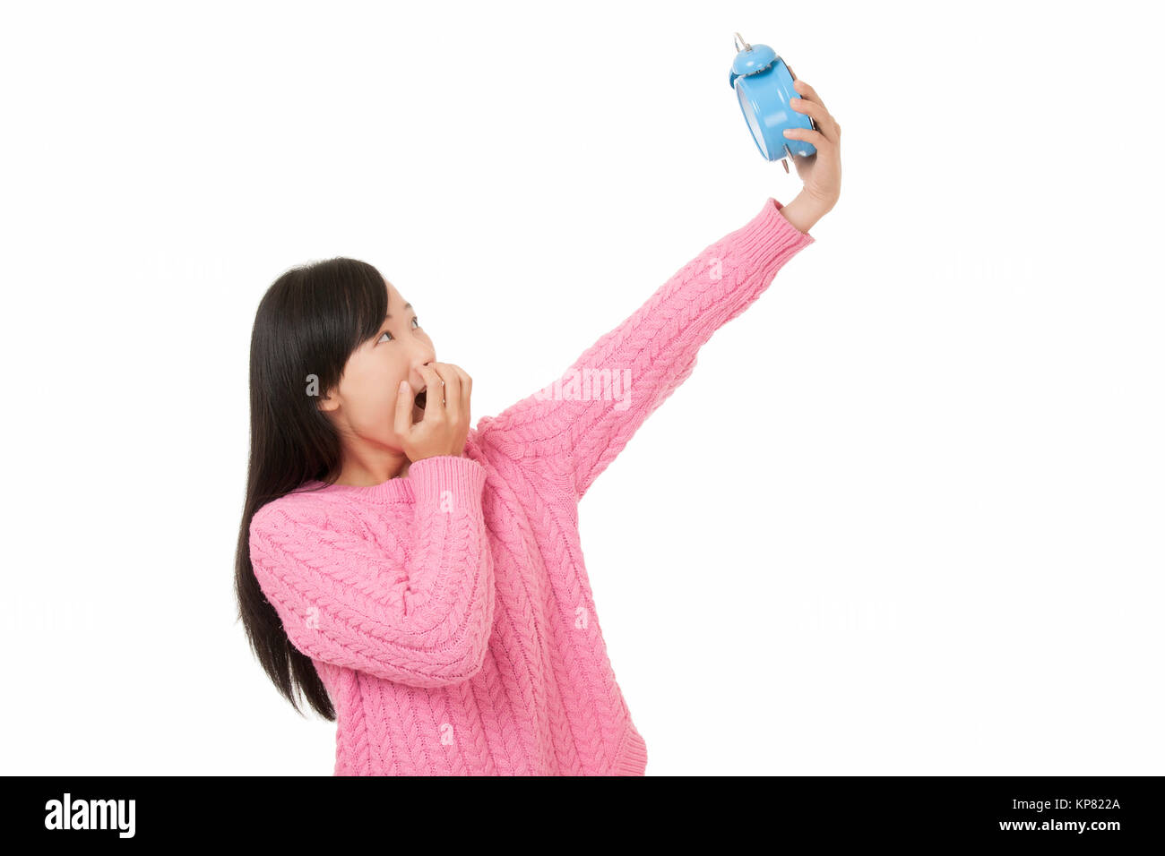 Beautiful Chinese woman holding a blue alarm clock and looking surpresed isolated on a white background Stock Photo