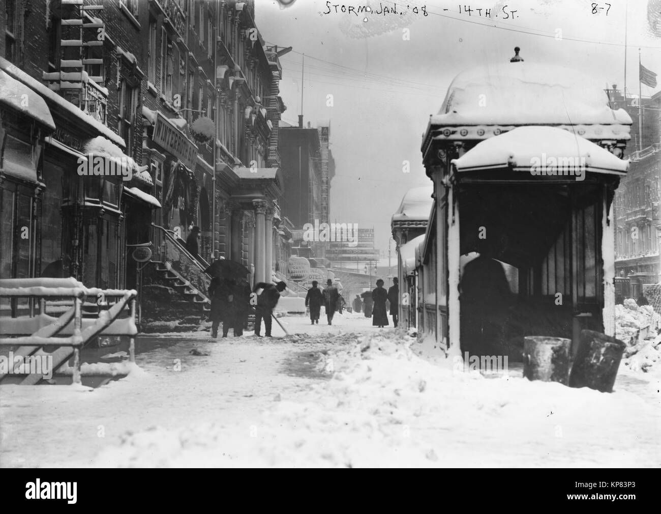 Man shoveling snow and people walking along 14th street in winter 1908